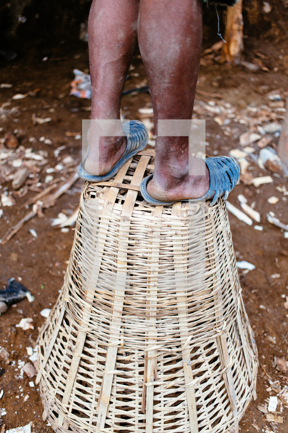 legs standing on a straw basket in Kalikhola Village 