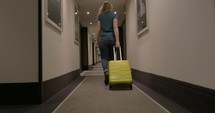 Woman walking along the hotel passage with trolley bag
