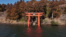 Waterside Torii Gate with Vibrant Autumn Trees in Serene Japanese Lake