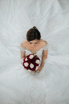 portrait of a bride holding a bouquet of red and white roses 