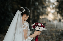 bride holding a bouquet of red and white roses 