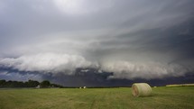A Dark, Powerful Storm Quickly Moves Closer Over Farm Land Turning The Sky Dark.