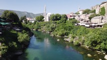 Aerial fly under Stari Most Bridge with tourist crowd in Mostar, Bosnia