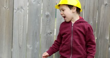 Toddler boy in construction worker outfit plays outdoors in backyard - close up