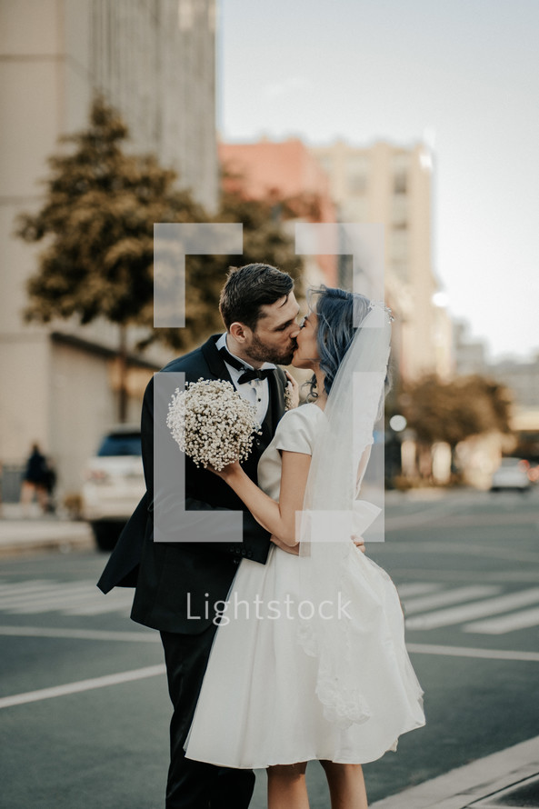 bride and groom kissing in a city 