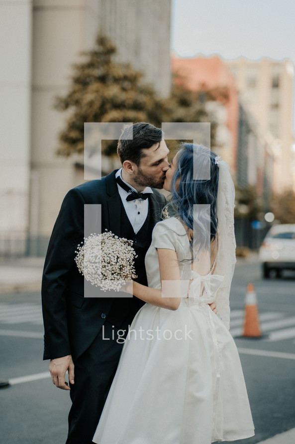 a bride and groom kissing in a city 