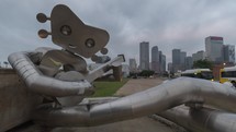 Time lapse of street traffic behind the Traveling Man metal statue in Dallas, Texas.