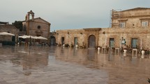 Marzamemi main square with church and outdoor restaurant after rain