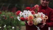 Smiling Young Woman Carrying A Bucket Of Cut Flowers Dahlias Cosmos Zinnias