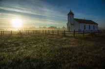 morning sun over a white rural church 