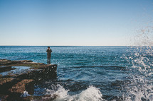 man standing on a rock by the ocean 