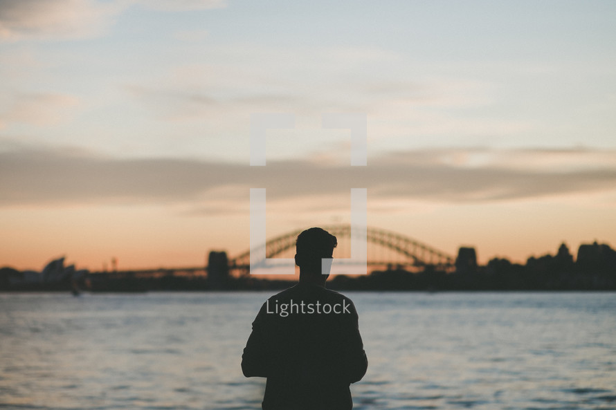 silhouette of a man standing in front of a bridge 