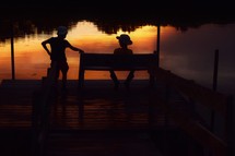 kids sitting on a dock at sunset 
