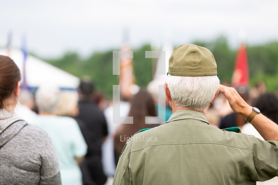 Veteran saluting flag at outdoor event