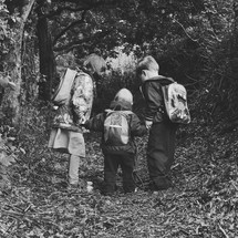 siblings with backpacks holding hands outdoors 