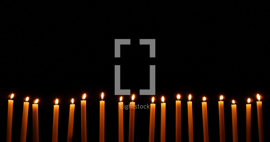 row of Christmas candles against black 