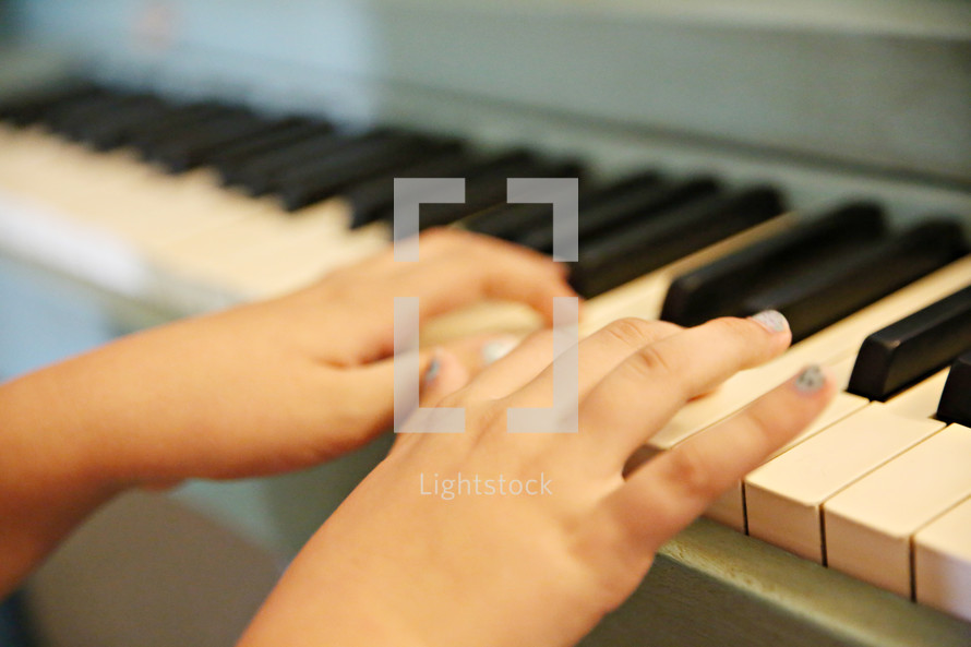 child's hands on a piano 