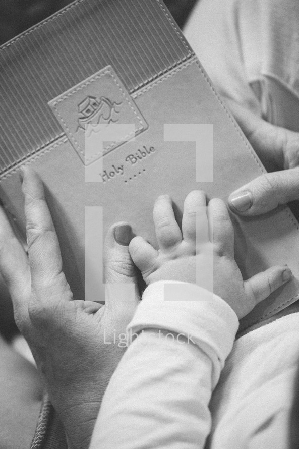 mother and infants hands on a Bible