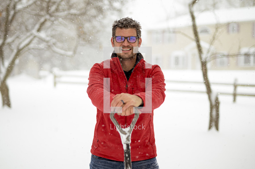 man with a shovel standing in snow 