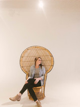a woman sitting in a wicker chair 