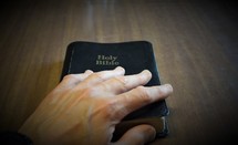 a man putting a hand on a Bible 