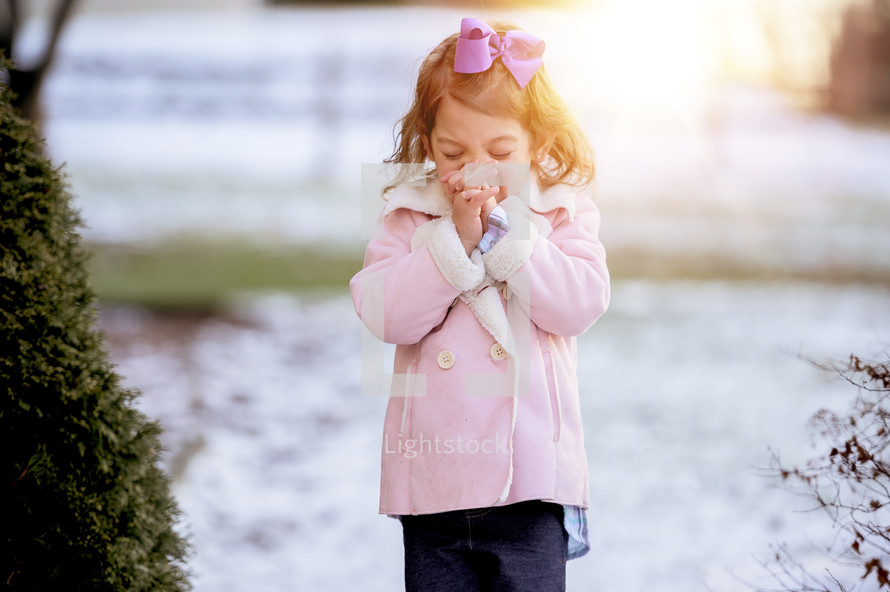 toddler girl standing outdoors praying in winter 