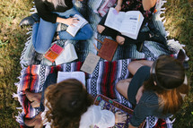 young women sitting on a blanket outdoors reading Bibles 