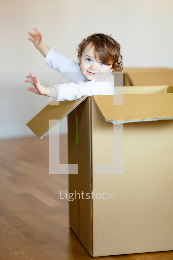 toddler playing in a cardboard box 