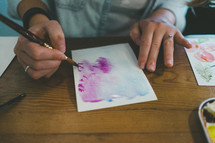 a woman painting with watercolors 