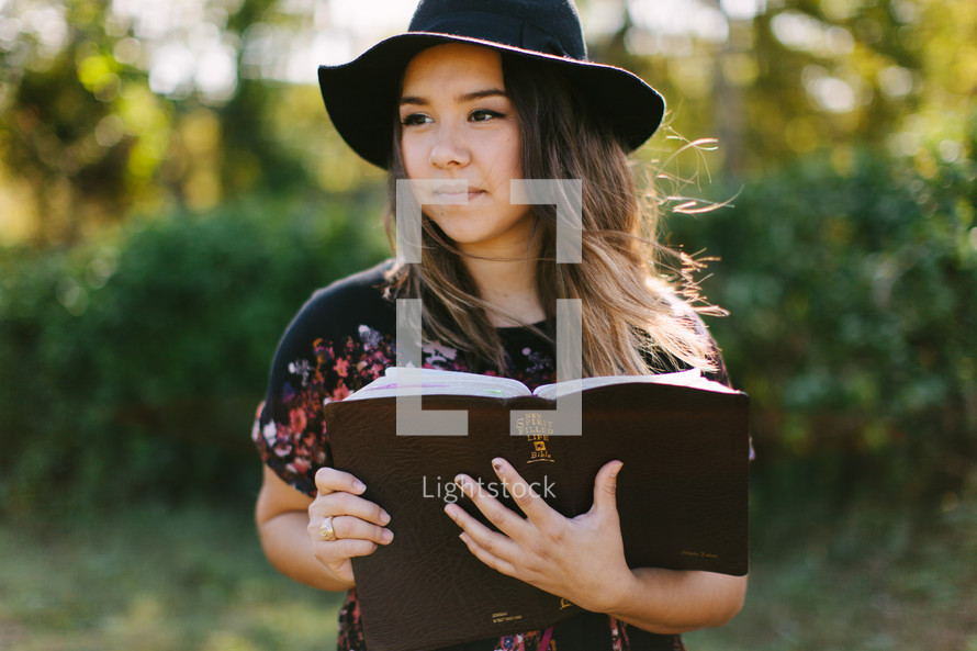 a teen girl in a hat reading a Bible 