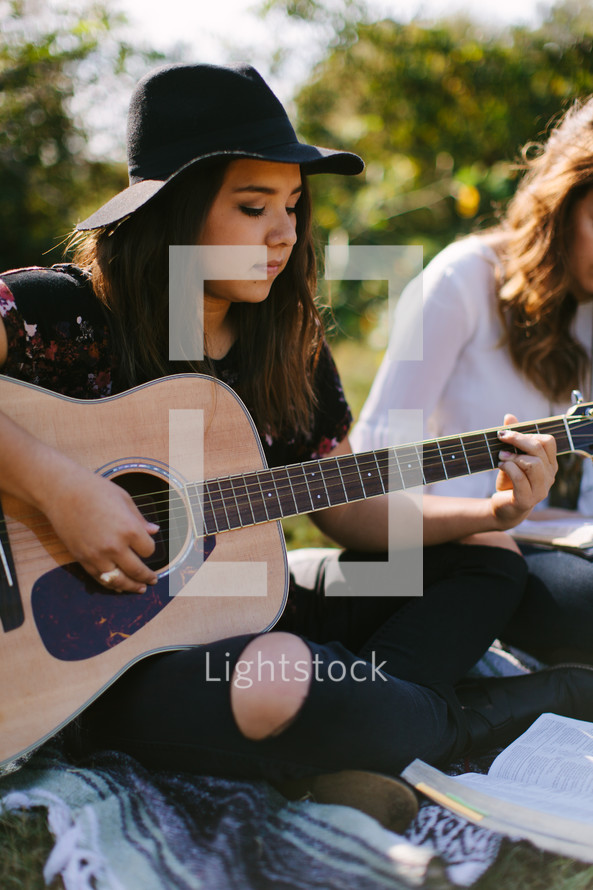 teen girl playing a guitar on a blanket 