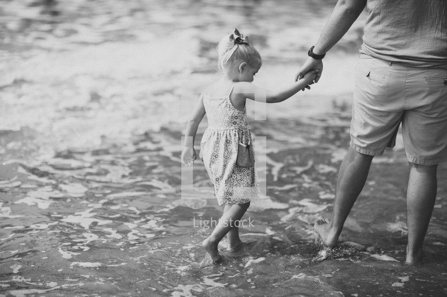 father and daughter walking holding hands on a beach 