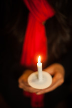 A woman holding a candle at a candlelight service 