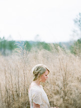 woman standing in a field of tall grasses and weeds 