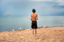 teen boy standing on a beach 