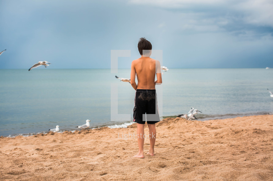 teen boy standing on a beach 