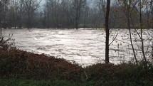 Large river flooding, rushing water flowing at high speed