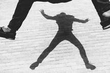 A young adult jumping up in the air - His shadow appearing on a brick wall