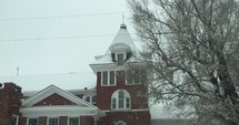 An old, brick church building with slow motion snow flakes falling. Snowflakes fall in dramatic, cinematic slow motion.
