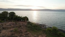 Drone flying over the Sea of Galilee at sunrise grasses and lake water biblical scene idilic peaceful rest Jesus Christ 