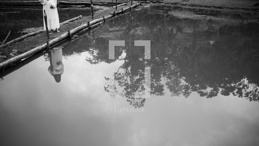 reflection of a woman and tree in pond water 