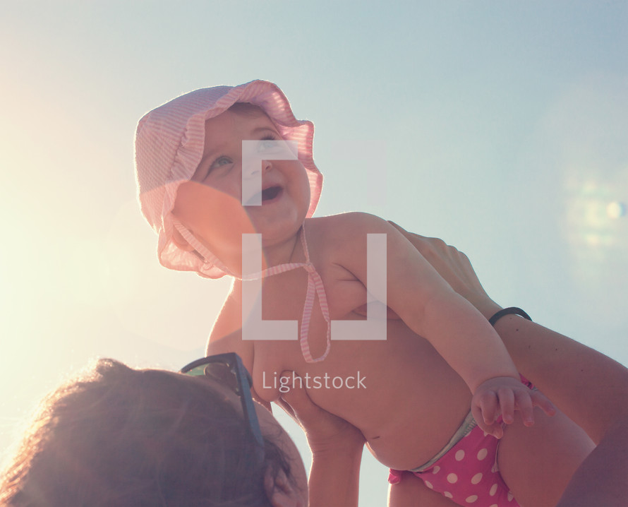 baby girl with mom at the beach. Backlight and flare effect.