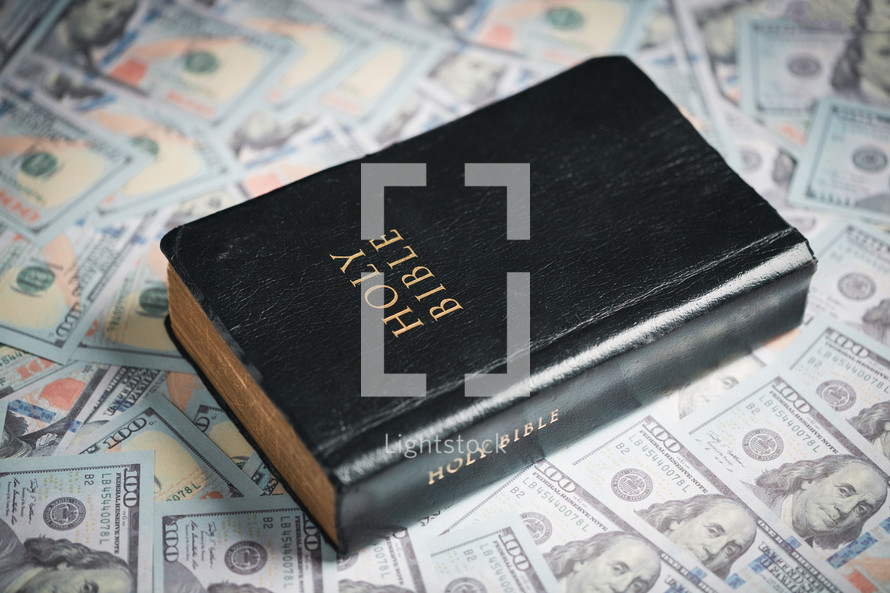 A Bible on top of one hundred dollar bills