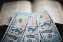 One hundred dollar bills on top of a Bible