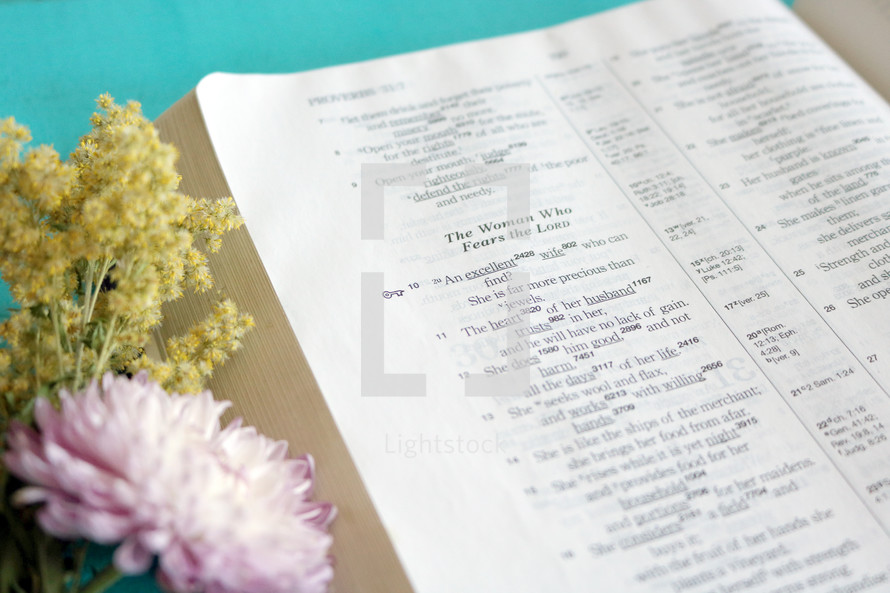 flowers and a Bible open to a the verses A woman who fears the Lord 