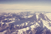 aerial view above a snow capped mountain peak 