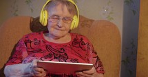 Modern grandmother with tablet pcC and headphones