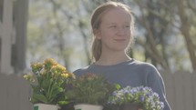 Young smiling woman planting and watering flowers on a warm spring day