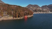 Waterside Torii Gate with Vibrant Autumn Trees in Serene Japanese Lake