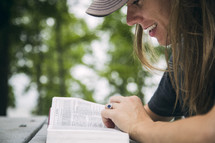 A young woman reading the Bible at a picnic table.